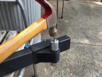 Hammer about to strike the aluminium insert of the bike stand.